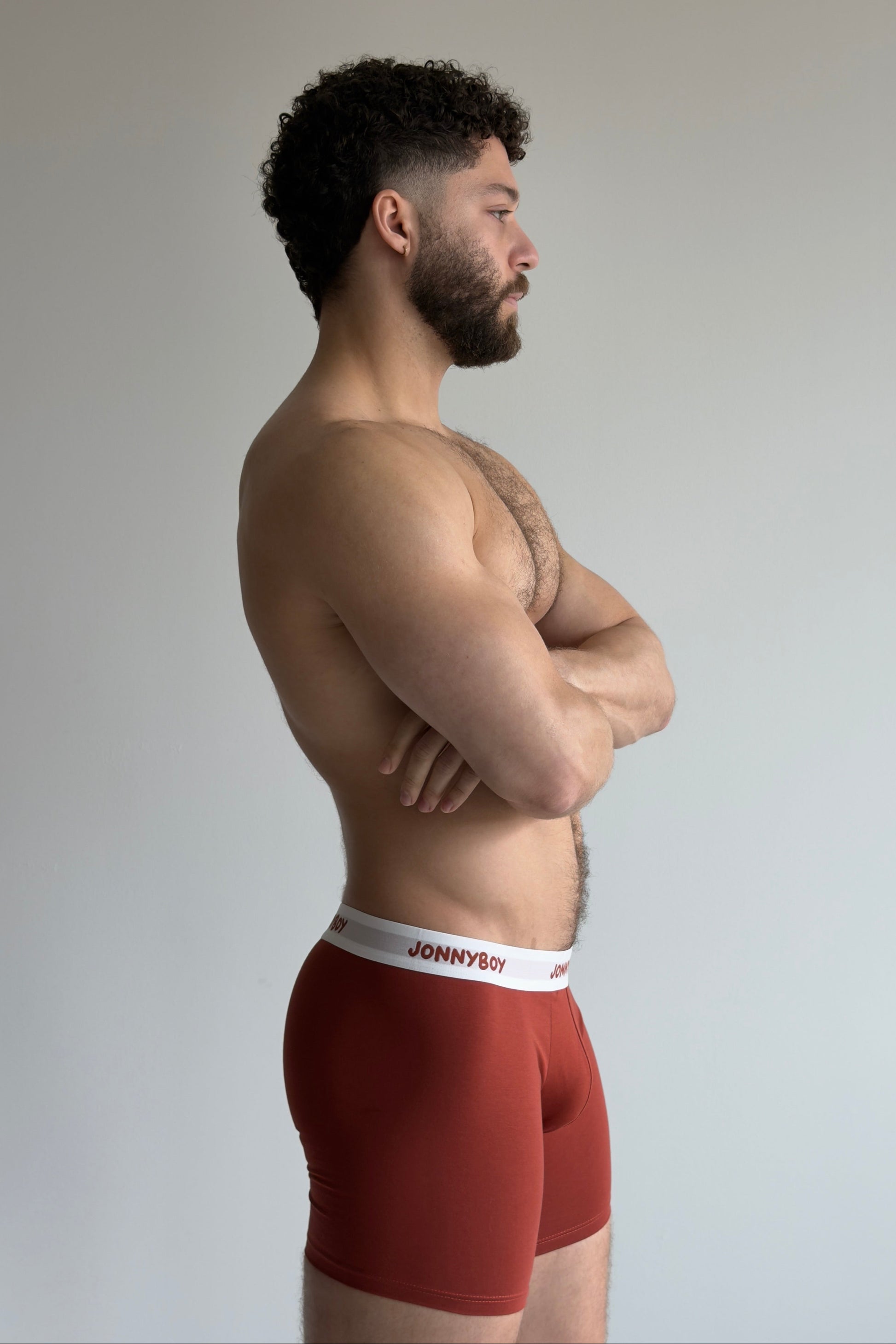 Man wearing red underwear with a white brand label on a plain background