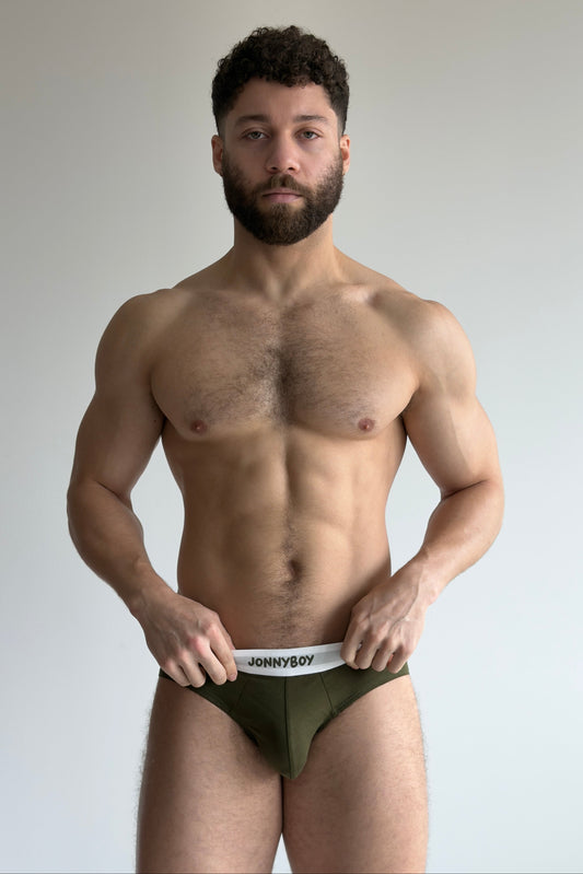 Man wearing a green underwear with 'JOHNNYBOY' label against a plain background