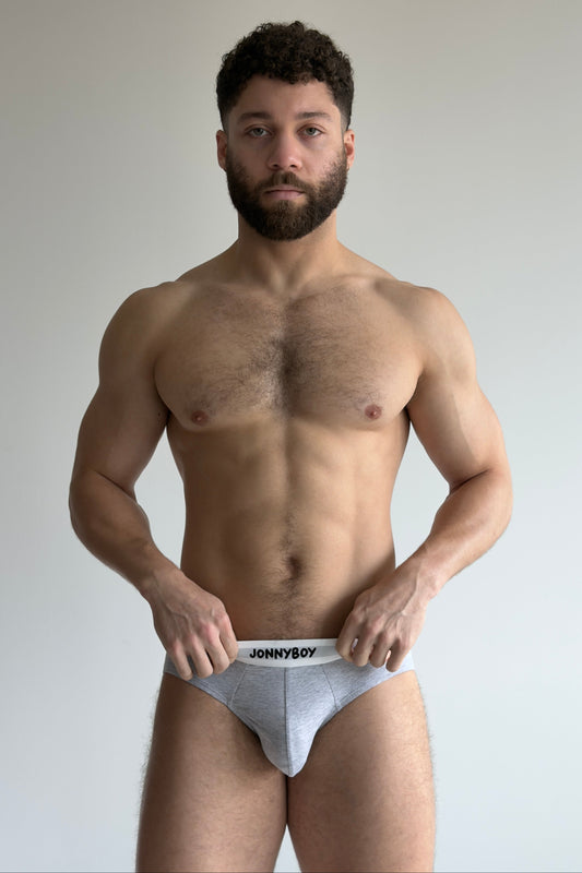 Man holding a pair of underwear with 'Johnny Boy' branding against a plain background